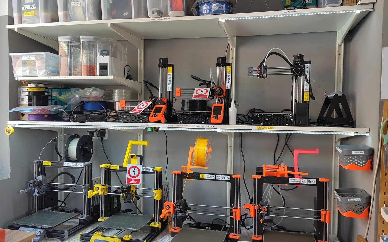 Estantes de un taller con impresoras 3D, rollos de filamento y cajas etiquetadas